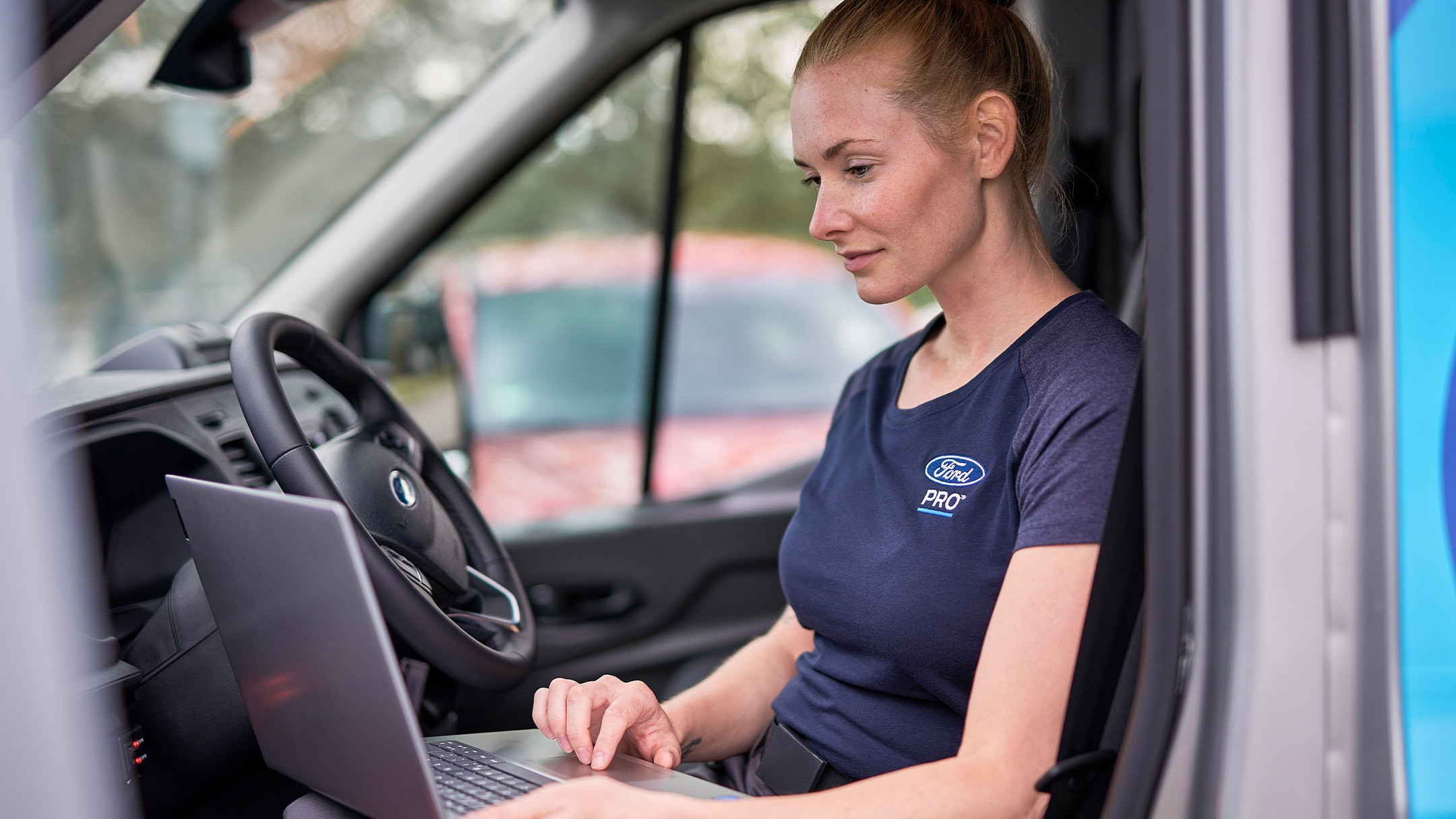 Eine Ford Pro Expertin checkt ihren Laptop während des Ford Services.
