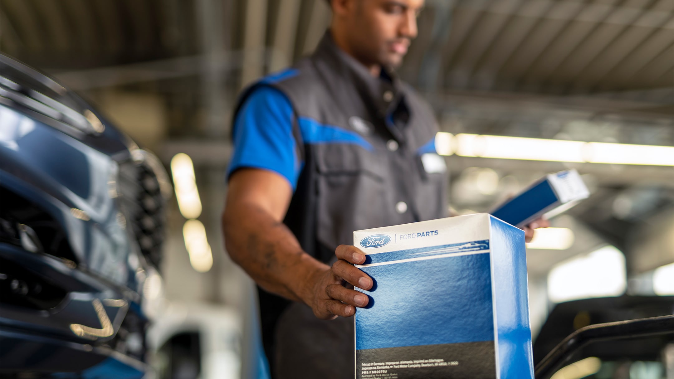 Ein Ford Techniker hält während des  Services die Verpackung eines Ford Originalteils in der Hand. 