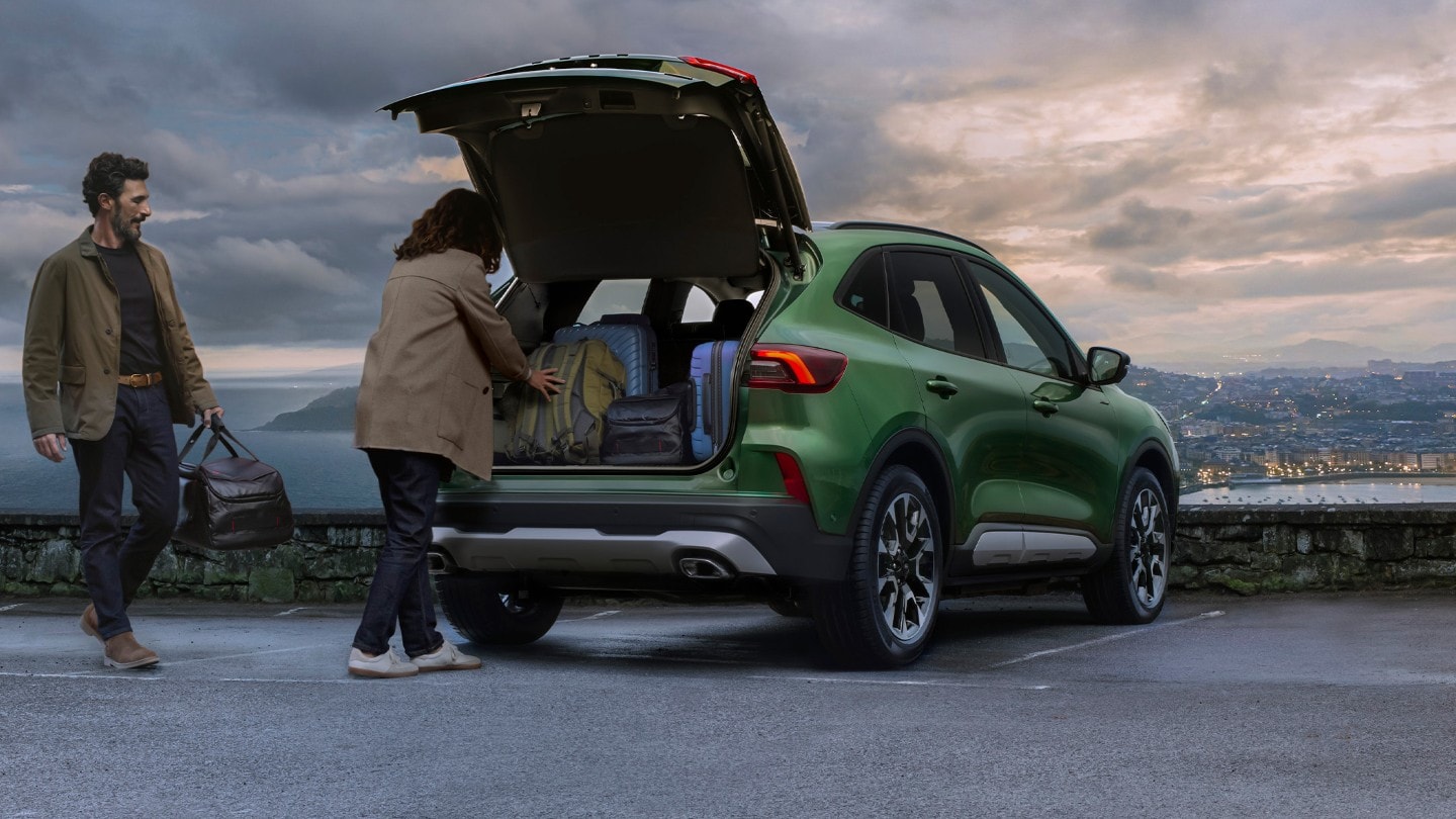 Ein Paar lädt Gepäck in einen Ford Kuga.