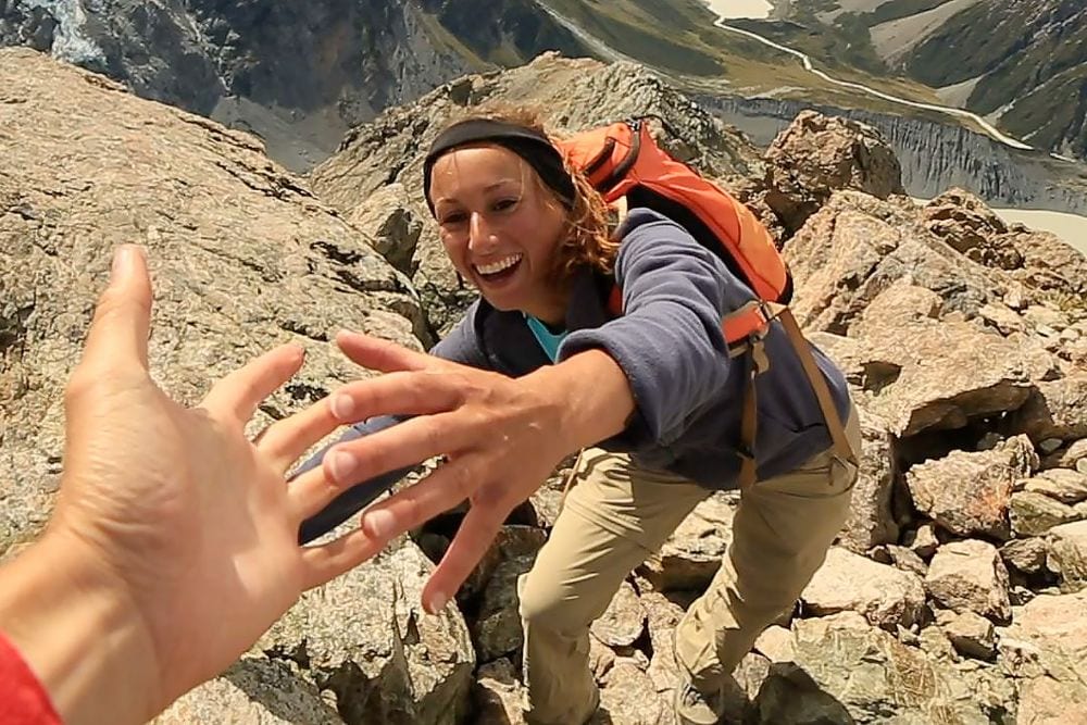 Wanderer reichen sich beim Bergsteigen die Hand