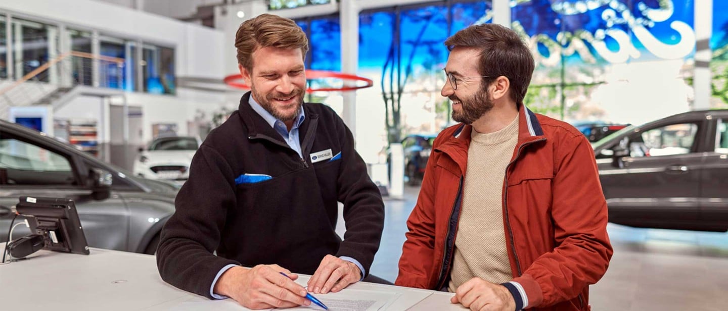 Mann beim Händler mit Kaufvertrag