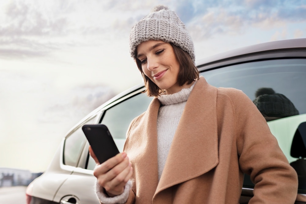 Lächelnde Frau, die auf ihr Smartphone schaut