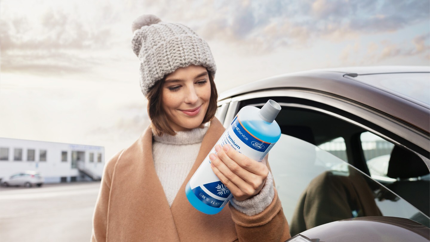 Frau mit einer Flasche Frostschutzmittel in der Hand