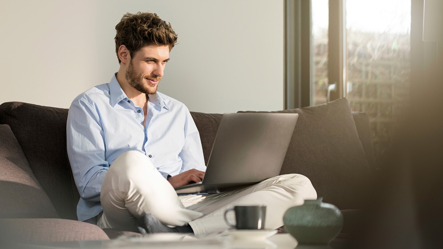 Mann mit Laptop sitzt auf einem Sofa